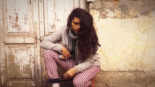 Young woman crouching against old door