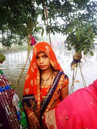 Portrait of young woman wearing sari while standing at lakeshore