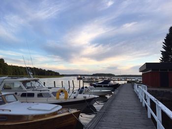 Boats moored at harbor against sky during sunset