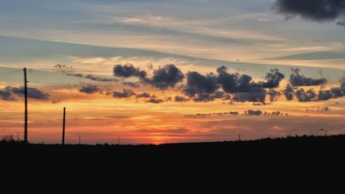 Scenic view of dramatic sky over silhouette landscape during sunset