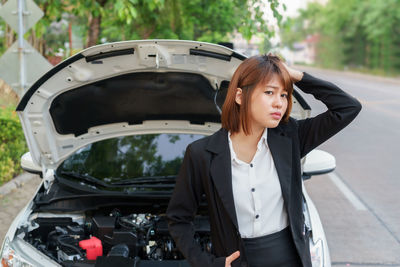 Portrait of worried businesswoman standing by car on street