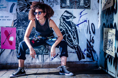 Full length of woman with graffiti on wall