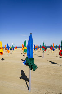 Rear view of umbrellas on beach against clear blue sky