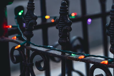 String of multicolor christmas lights on black vintage wrought and cast iron victorian fence