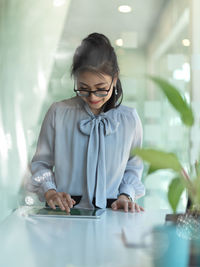 Smiling young businesswoman using digital tablet in office