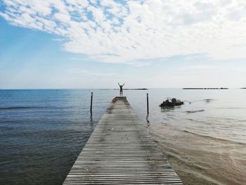 Wooden pier over sea against sky