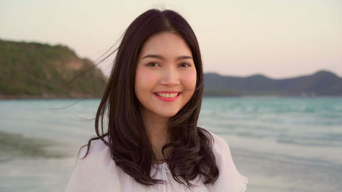 Portrait of smiling young woman against sea