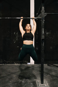 Full length of young woman exercising at gym