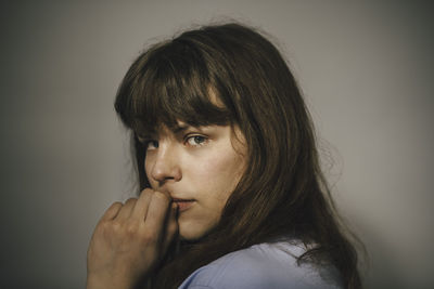 Portrait of young woman looking away against white background