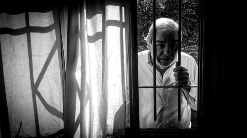 Close-up of girl standing against window at home