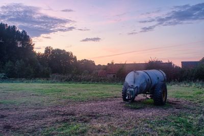 Tractor on field against sky during sunset