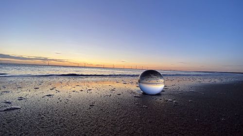 Surface level of beach against sky during sunset