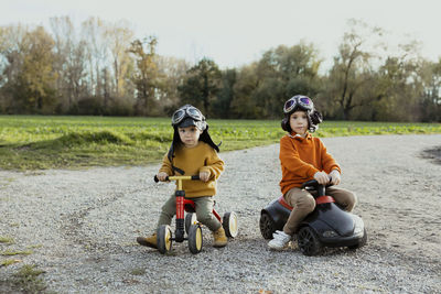 Baby boy on quadcycle by brother on bobby car