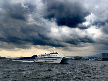 Boats in sea against cloudy sky