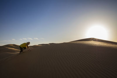 Senior woman climbing on sand dune at desert