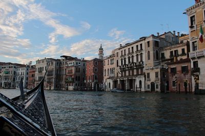 Canal in city against sky