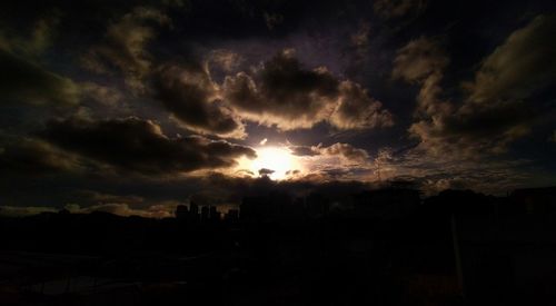 Silhouette landscape against dramatic sky during sunset