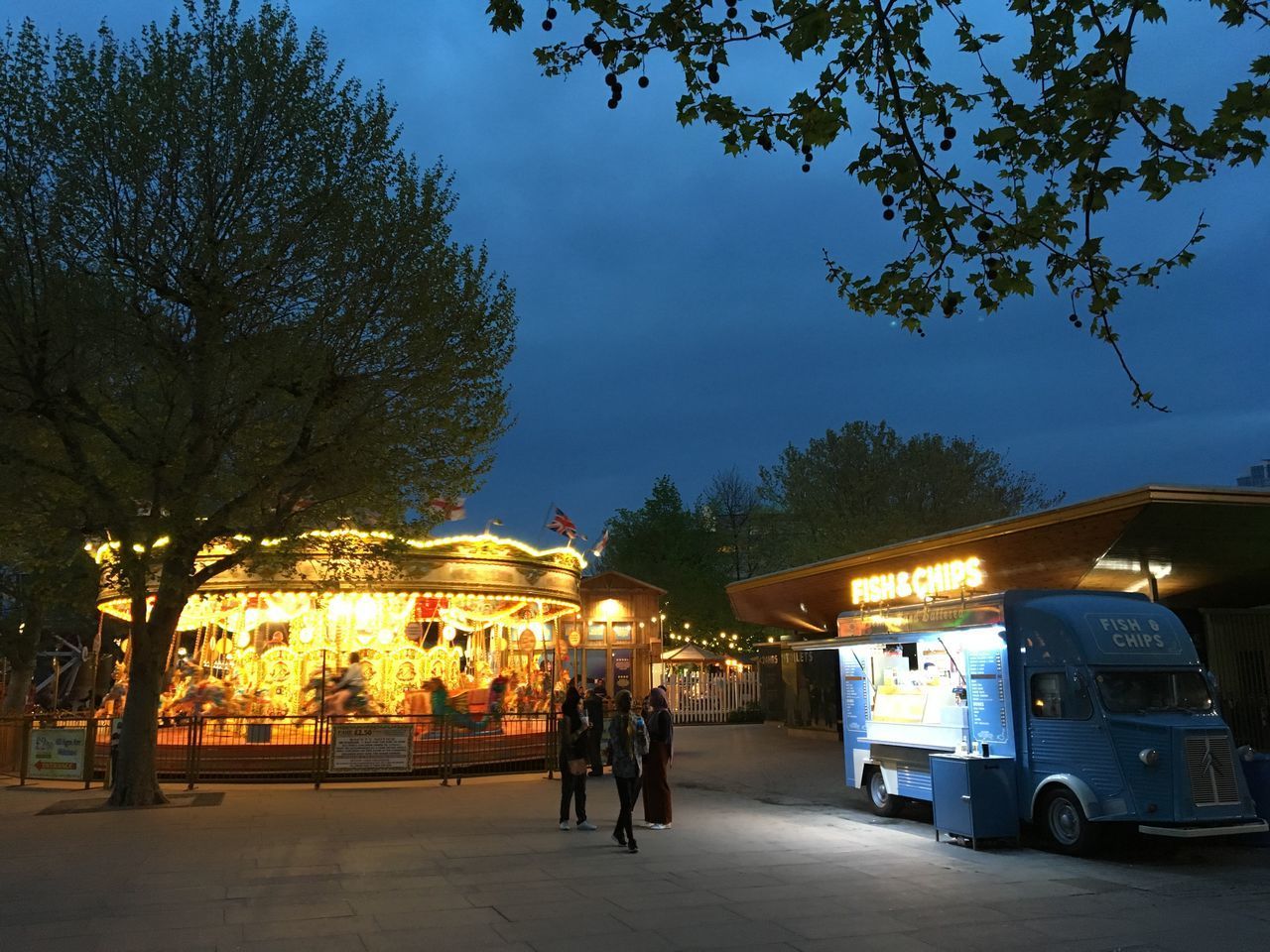 PEOPLE ON STREET AGAINST ILLUMINATED CITY AT NIGHT