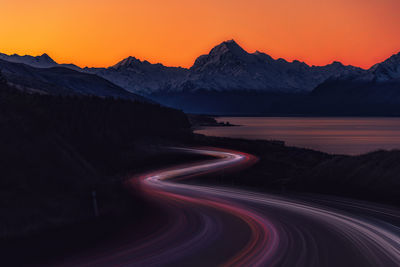 Light trails on road against sky at sunset