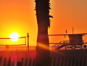 Silhouette built structure against orange sky