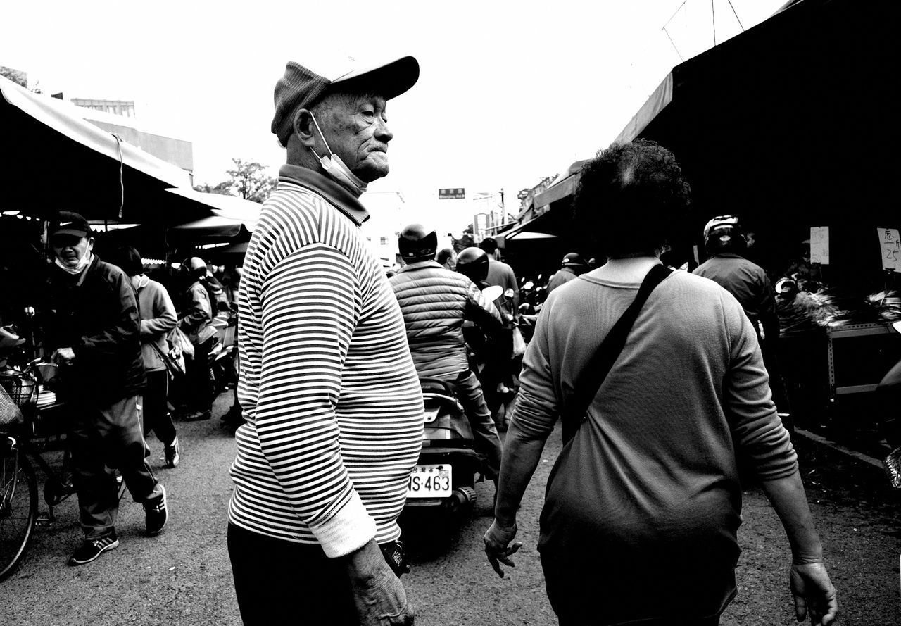 REAR VIEW OF PEOPLE WALKING ON STREET