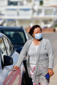 Woman standing by car in city