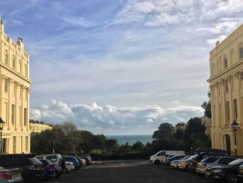 Cars on road by buildings against sky in city