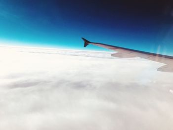 Airplane flying over clouds against blue sky