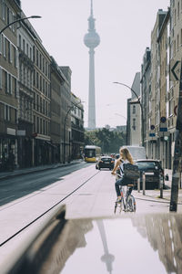 Rear view of businesswoman riding bicycle on street in city