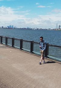 Young man walking on promenade against sky