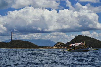 Boats in sea against cloudy sky