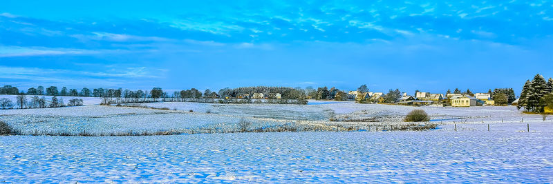 Scenic view of snow covered field against blue sky