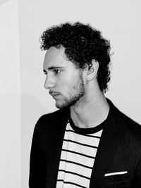 Portrait of young man looking away against wall