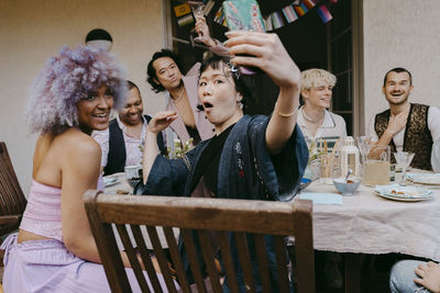 Transwoman taking selfie through smart phone with friends of lgbtq community during dinner party in back yard