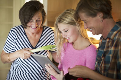 Three generation females searching recipe on digital tablet in kitchen