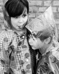 Portrait of smiling siblings in raincoat sanding outdoors