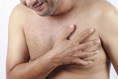 Midsection of shirtless man against white background