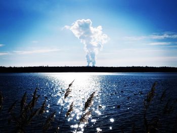 Smoke emitting from blue sky over lake