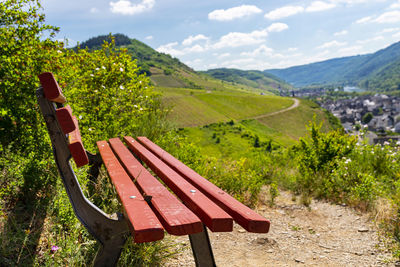 A red bench standing on the hill of the winery, in the background beautiful wineries in the spring.