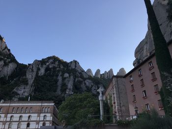 Low angle view of buildings and mountains against clear blue sky
