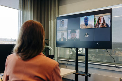 Rear view of businesswoman doing video conference with colleagues in coworking office