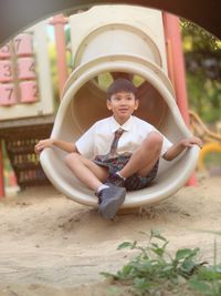 Cute boy sitting on slide at playground
