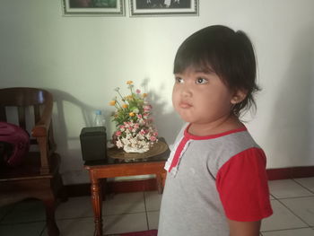 Portrait of cute girl sitting on table at home