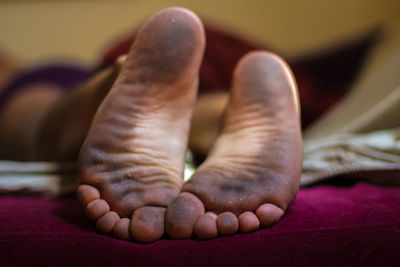 Close-up of messy feet of person lying in bed at home