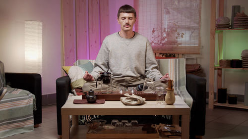 Man with closed eyes meditating at home