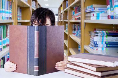 Girl reading book while sitting in library