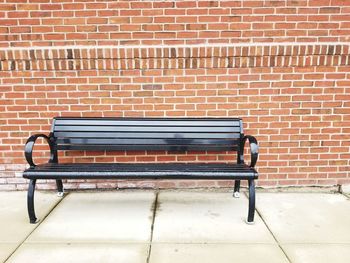 Empty bench against brick wall