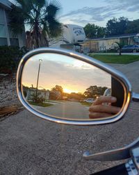 Reflection of man photographing on side-view mirror