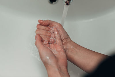 Cropped hand washing hands in sink