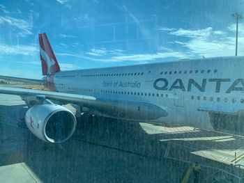 Airplane flying over airport runway against sky